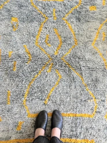 Alfombra bereber gris Beni Ouarain con líneas mostaza, de lana gruesa y formato pequeño.