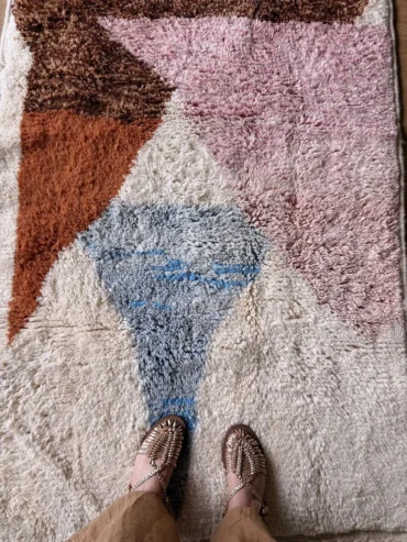 Alfombra bereber de lana con formas geométricas en tonos pastel sobre base cruda, ideal para espacios infantiles