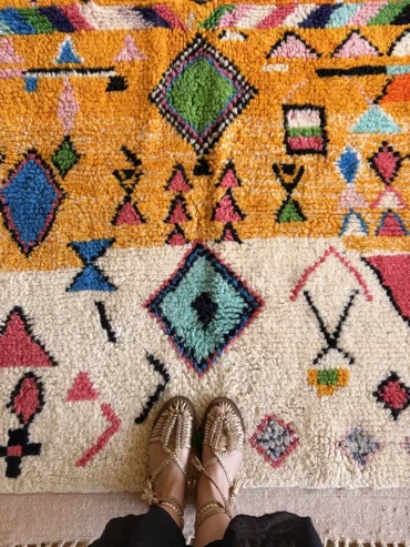 Alfombra bereber de lana con diseño étnico de rombos sobre base naranja, tejida a mano con colores intensos